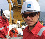 Researchers wearing hardhats on ship.